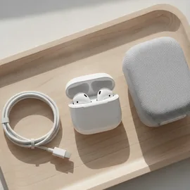 Kabellose Ohrhörer, ein Ladekabel und ein kleiner Lautsprecher auf einem Holztablett